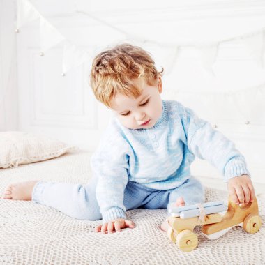 Çocuk çocuk odasında bir ahşap oyuncak araba ile oynamak.