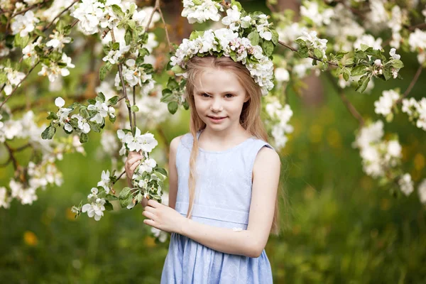 Blosoming リンゴの木のある庭園で青いドレスの美しい少女 リンゴの木の枝を持ってかわいい女の子 — ストック写真