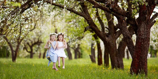 花の咲く古いアップル ツリー庭のブランコに乗る楽しみを持つ つのかわいい女の子 晴れた日 春の野外活動子供のため — ストック写真