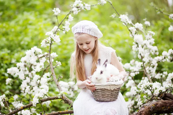 春の花庭で白いウサギと遊ぶ白いドレスを着た美しい少女 春の楽しい子供のための活動 イースターの時期 — ストック写真
