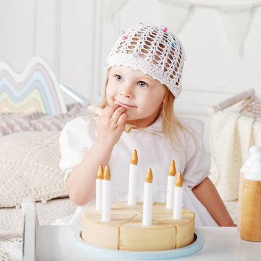 Ahşap oyuncak pastayla oynayan kız çocuk. Doğal oyuncaklar ile küçük şirin kız.