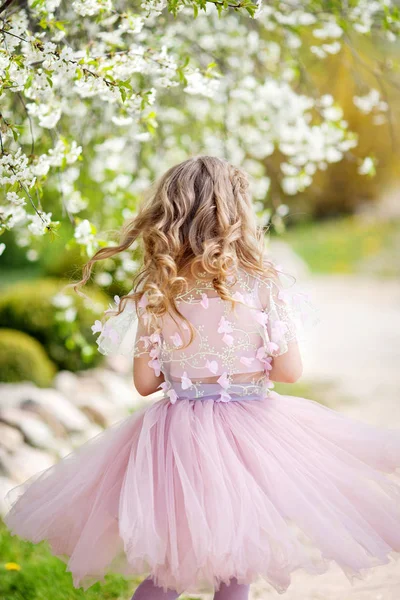 Blosoming 나무와 정원에서 분홍색 드레스에 재미와 즐기는 귀여운 — 스톡 사진