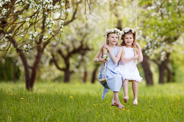 两个可爱的女孩在开花的老苹果树花园荡秋千上玩的乐趣 儿童春季户外活动 — 图库照片