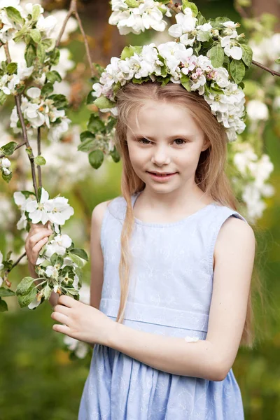 Piękna młoda dziewczyna w niebieskiej sukience w ogrodzie z blosoming — Zdjęcie stockowe