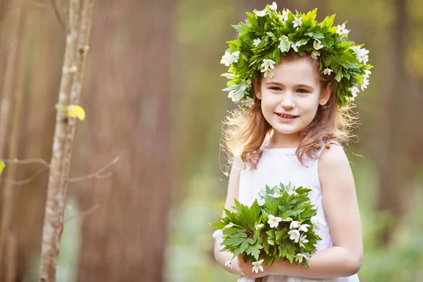 Красива маленька дівчинка в білій сукні ходить у весняному лісі — стокове фото