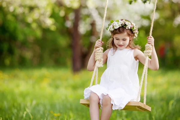 Aranyos fiatal lány, a virágzó régi Alma-t swing szórakozás — Stock Fotó