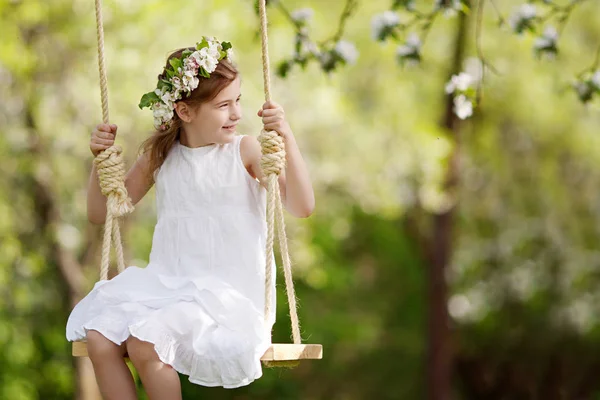 Мила молода дівчина розважається на гойдалці в квітучому старому яблуці т — стокове фото