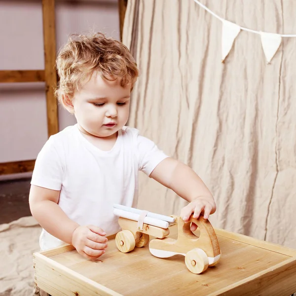 Παιδί αγόρι παίζει στο δωμάτιό του με ένα ξύλινο παιχνίδι αυτοκίνητο — Φωτογραφία Αρχείου