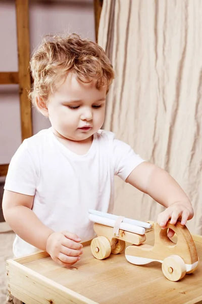 Kind jongen spelen in zijn kamer met een houten speelgoedauto — Stockfoto