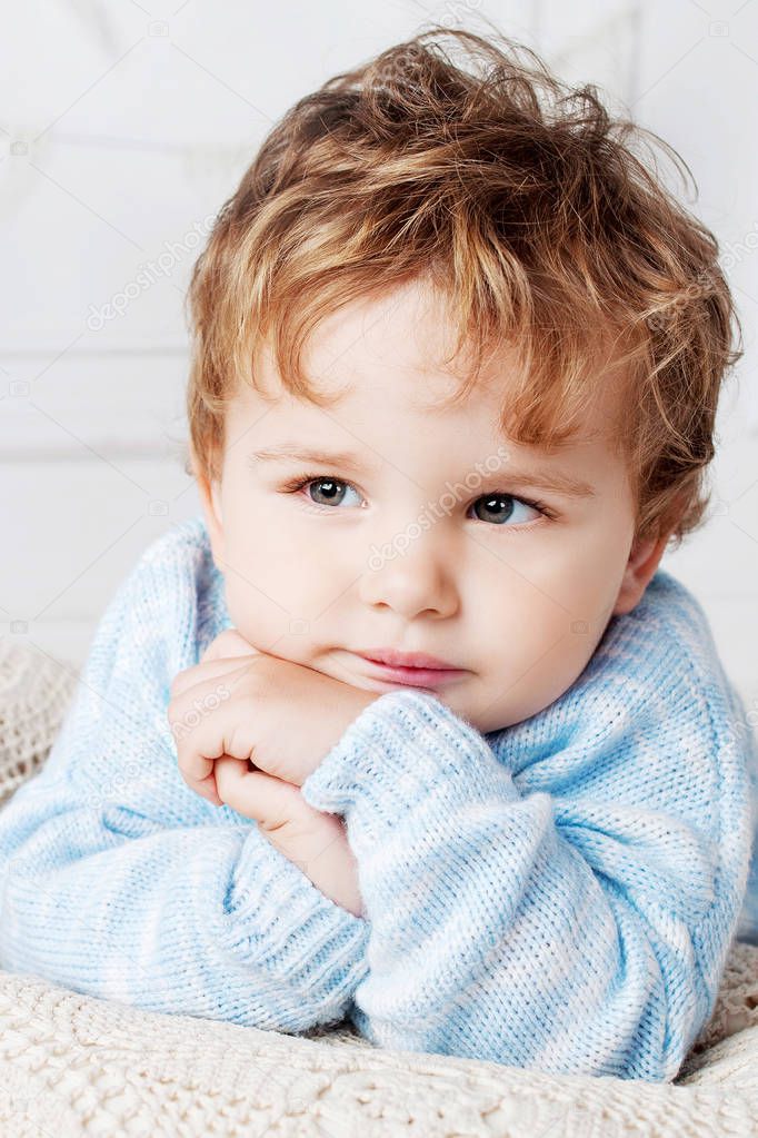 Portrait of happy adorable baby boy on the bed in his room. Thou