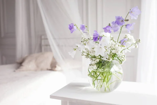 Vaso di vetro con fiori lilla e bianco in luce accogliente camera da letto — Foto Stock