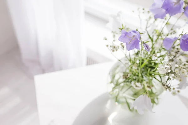 Glazen vaas met lila en wit floweers in lichte gezellige slaapkamer — Stockfoto