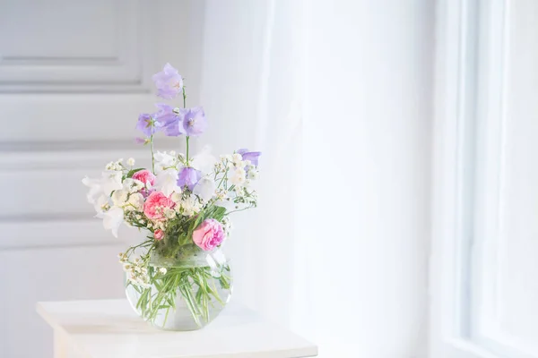 Mesa de cabeceira, vaso com flores cor de rosa e lilás. Backgrou branco — Fotografia de Stock