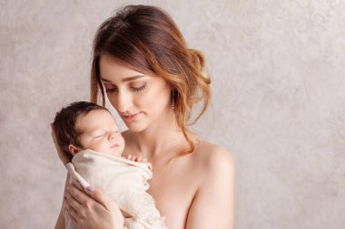 Onun kollarında yeni doğmuş bir bebek tutan genç ve güzel kadın. Portre 