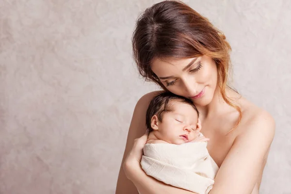 Hübsche junge Frau mit einem neugeborenen Baby auf dem Arm. Porträt — Stockfoto