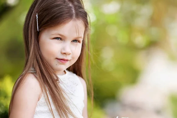 Bella sorridente bambina in abito crema, contro il verde di s — Foto Stock