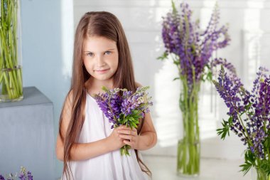 Güzel küçük duygusal kız mor çiçekler arasında oturur. Bir flo