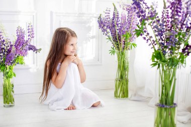 Mor çiçekler arasında siting güzel küçük duygusal bir kız. A 