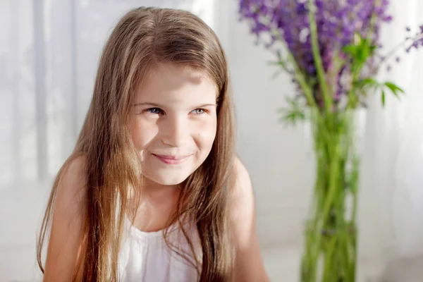 Porträt eines hübschen kleinen emotionalen Mädchens inmitten violetter Blüten.cl — Stockfoto