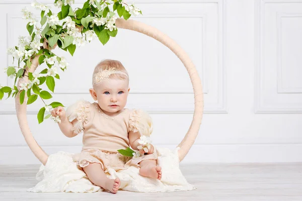 Niña bonita con ojos azules se sienta en un piso con flores o — Foto de Stock