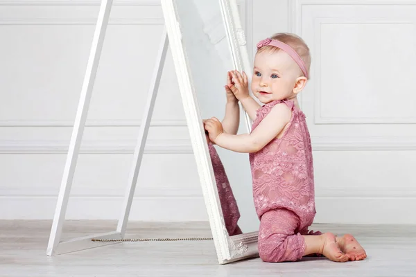 Little pretty girl plays with a big mirror — Stock Photo, Image