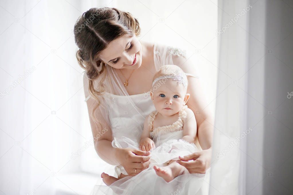Little girl in a tender embrace of mother at the window. Mother 