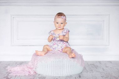 Mavi gözlü küçük güzel kız yastıklı bir taburede oturur. Kopya s