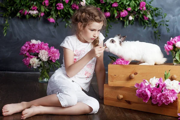 Маленькая девочка играет с настоящим кроликом. Ребенок и белый кролик на Е — стоковое фото
