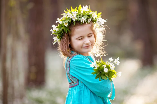 Schönes kleines Mädchen in blauem Kleid, das im Frühlingswald spaziert — Stockfoto