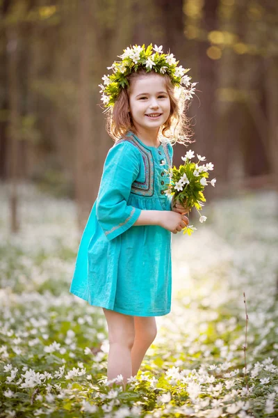 Schönes kleines Mädchen in blauem Kleid, das im Frühlingswald spaziert — Stockfoto