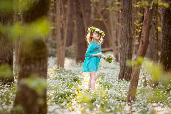 美丽的小女孩在蓝色礼服走在春天的木头 — 图库照片
