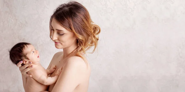 Досить молода жінка тримає новонароджену дитину на руках. Портрет — стокове фото
