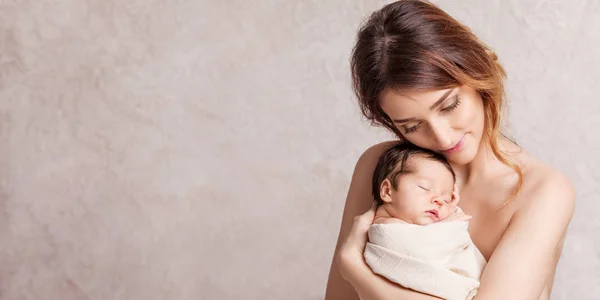 Mujer joven y bonita sosteniendo a un bebé recién nacido en sus brazos. Retrato — Foto de Stock