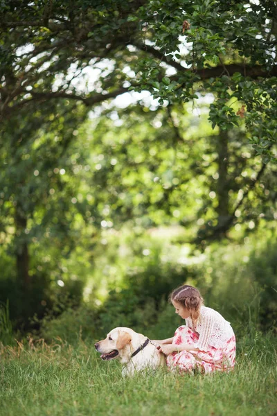 Süßes lächelndes kleines Mädchen umarmt und bügelt Labrador in der su — Stockfoto