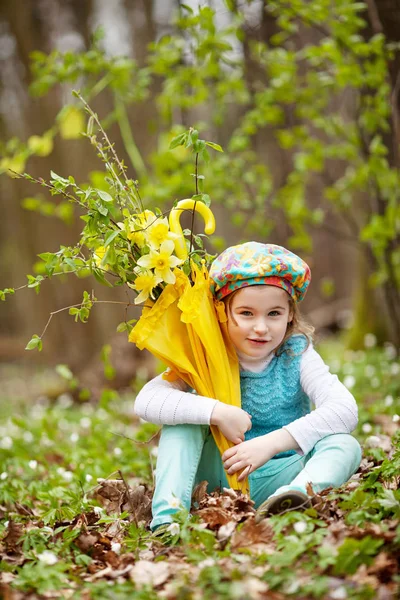 Little cute girl with narcissus flowers in a spring garden.  Chi — Stock Photo, Image