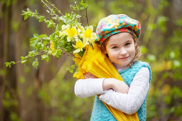 Pequena menina bonito com flores narciso em um jardim de primavera. Qui — Fotografia de Stock