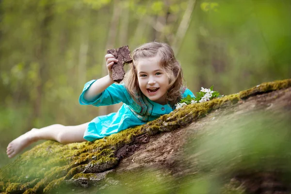 Krásná malá dívka v modrých šatech, procházky v lese na jaře — Stock fotografie