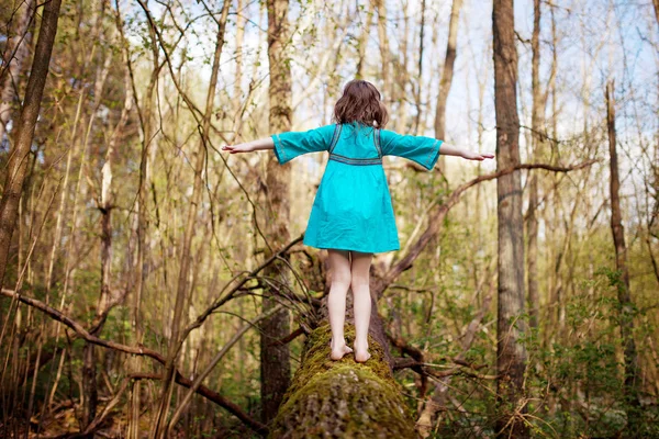 Menina bonita em um vestido azul andando na madeira da mola — Fotografia de Stock