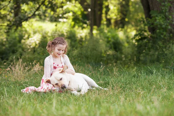 Söt leende liten flicka kramar och Strykningsservice labrador i su — Stockfoto