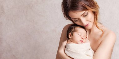 Onun kollarında yeni doğmuş bir bebek tutan genç ve güzel kadın. Portre 