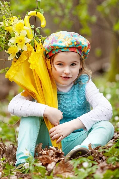 Malá roztomilá dívka s květy narcisu v jarní zahradě. Chi — Stock fotografie