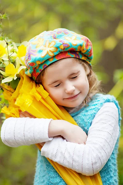 Malá roztomilá dívka s květy narcisu v jarní zahradě. Chi — Stock fotografie