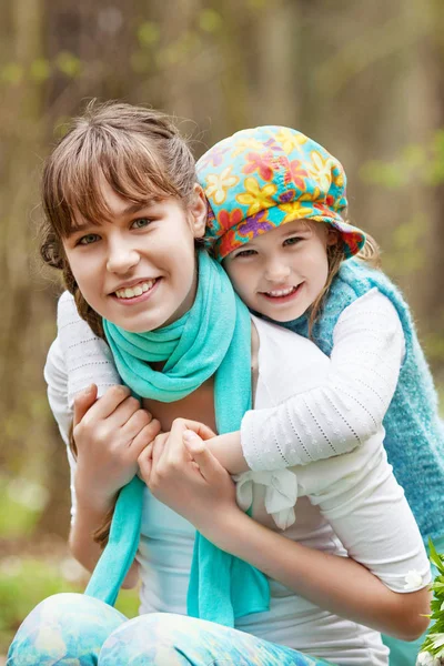 Portrait of two sisters  in the spring forest. Smiling cute sist