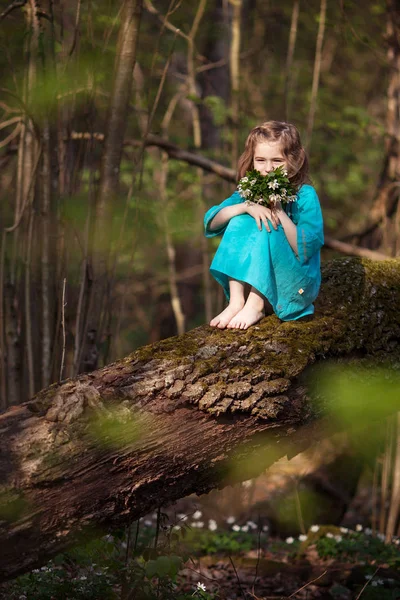สาวน้อยที่สวยงามในชุดสีฟ้า เดินในไม้ฤดูใบไม้ผลิ — ภาพถ่ายสต็อก