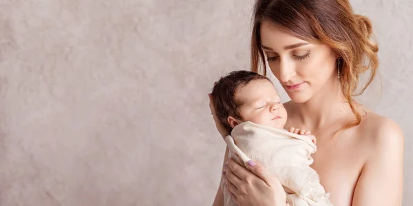 Pretty young woman holding a newborn baby in her arms. Portrait — Stock Photo, Image