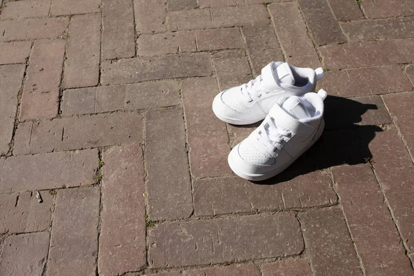 Witte sneakers op de achtergrond van de oude tegel. Kinderen Litt — Stockfoto