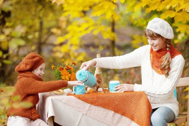 Sonbahar parkında pikniğe iki sevimli kız kardeş. Sevimli küçük kız