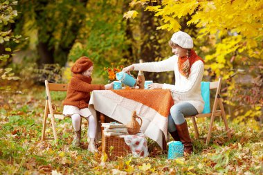 Sonbahar parkında pikniğe iki sevimli kız kardeş. Sevimli küçük kız