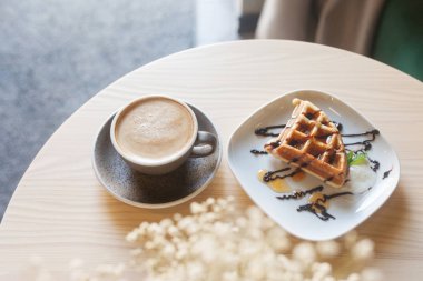 Hafif ahşap masada kahve ve belçika waffle tabağı