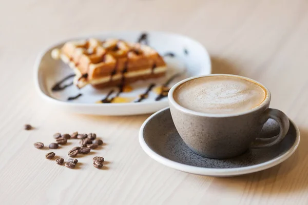 Secangkir kopi dan sepiring wafel belgian di meja kayu ringan — Stok Foto